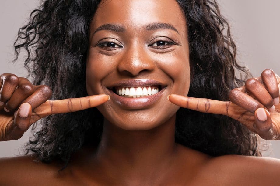 a woman points to her white teeth