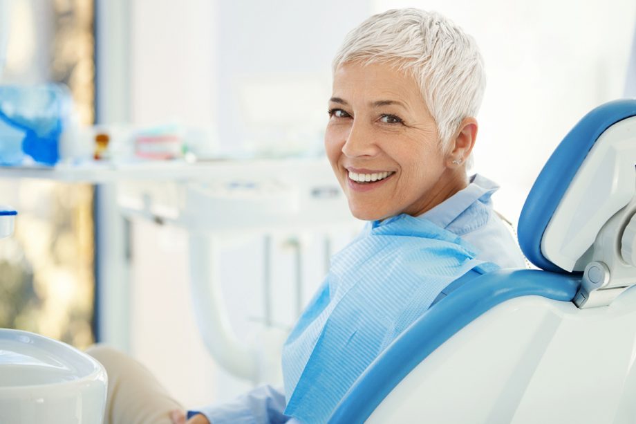an older woman smiles in a dental chair